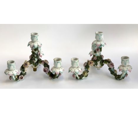 A pair of porcelain floral encrusted three arm candlestick holders (af), 20cmH 