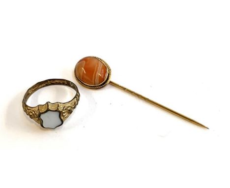 A gilt metal ring set with a blank white agate shield shaped intaglio, size Q; together with a yellow metal mounted stick pin