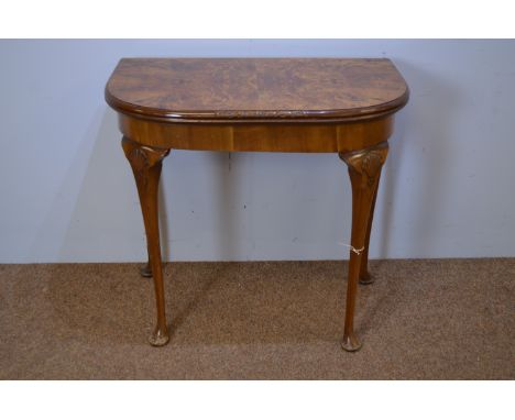 A Georgian style burr walnut card table, the D-shaped hinged swivel top opening to reveal a baise-lined playing surface, rais