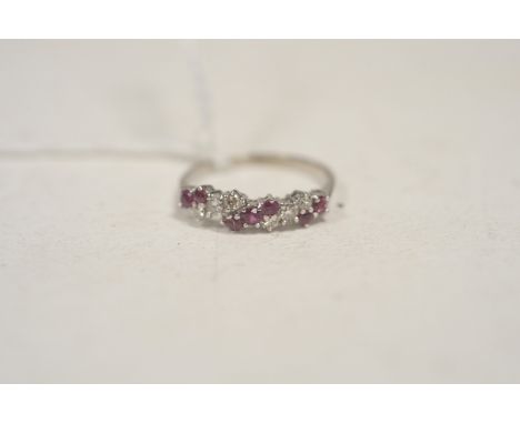 A diamond and ruby ring, the brilliant-cut diamonds and circular facet-cut rubies set in diagonal rows, on white metal shank 