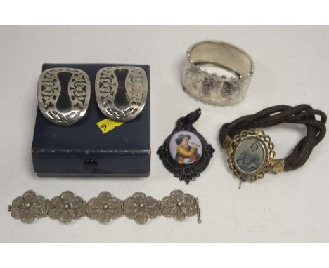 A plaited hair bracelet with giltmetal mount inset picture locket; a silver cuff bangle with floral decoration; a white metal