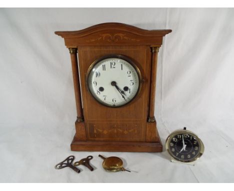 An Edwardian mahogany cased mantel clock, the case having decorative inlays, curved top and flanked by columns, white enamel 
