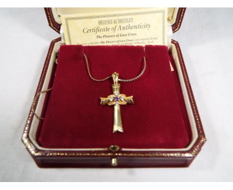A lady's 9 carat gold cross entitled "The Flowers of Lovecross" with certificate of authenticity from Brooks and Bentley, sto