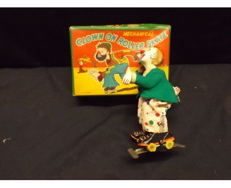 A tin plate clockwork roller skating clown, boxed.