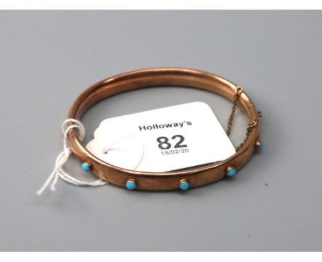A late Victorian rose gold coloured bangle, the hollow bangle set with five circular turquoise stones, push button clasp Some
