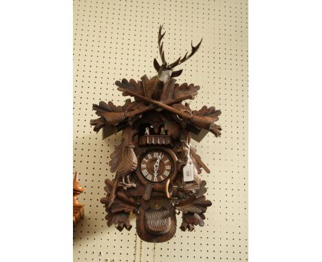An early 20th century Black Forest carved wall clock, with painted rotating peasant figures