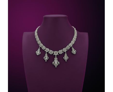 A late Victorian diamond necklace, formed with graduated circular links, each centred with a cushion-shaped diamond within a 