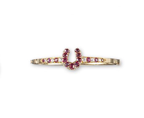An Edwardian ruby and diamond set gold hinged bangle, designed as a horseshoe which detaches and could be worn as a brooch (n