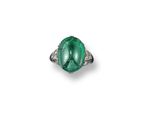 An emerald and diamond ring, the cabochon emerald is set with smaller shoulder diamonds in platinum. Size O 1/2.