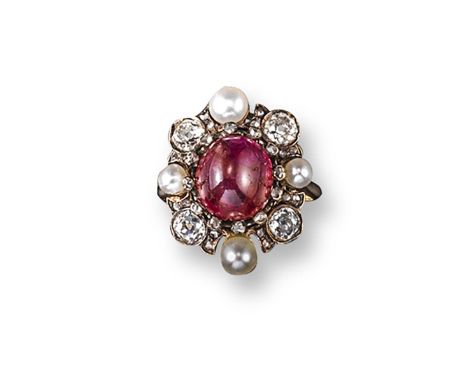 A ruby, pearl and diamond cluster ring, the cabochon ruby is set within a surround of alternately-set cushion-shaped diamonds