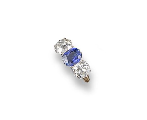 A sapphire and diamond three stone ring, the oval-shaped sapphire is set between two cushion-shaped diamonds in yellow gold. 