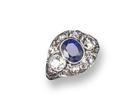 A sapphire and diamond cluster ring, the oval-shaped sapphire is millegrain-set within two cushion-shaped diamonds and a furt