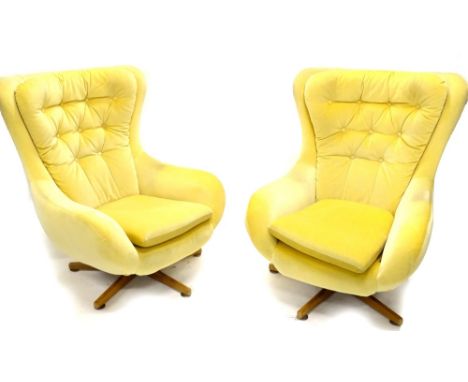 A pair of 1950/60's revolving armchairs, each with a button back and star shaped teak base, possibly G-Plan.  The upholstery 