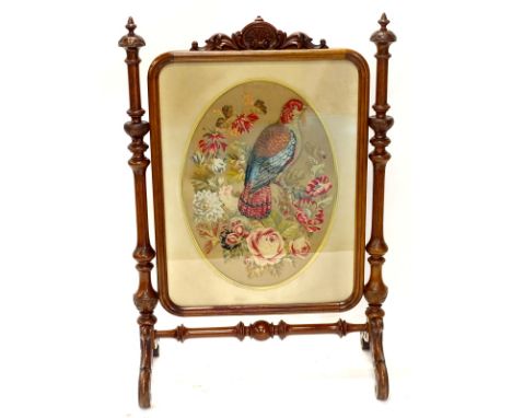 A large Victorian walnut firescreen, the rectangular banner with a raised woolwork picture, depicting a parrot on a branch wi