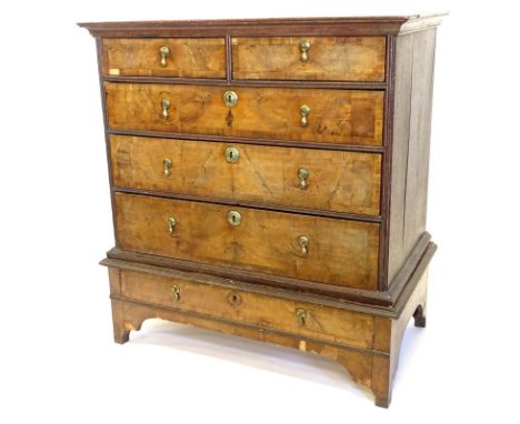 An 18thC walnut chest on stand, the top with a moulded cornice with two short and three long cross banded drawers, with brass