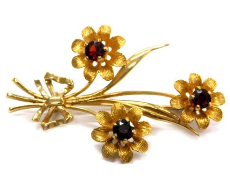 A triple flower brooch, in a triple length spray, each set with garnet, approx 5mm diameter, each flower with five claw setti