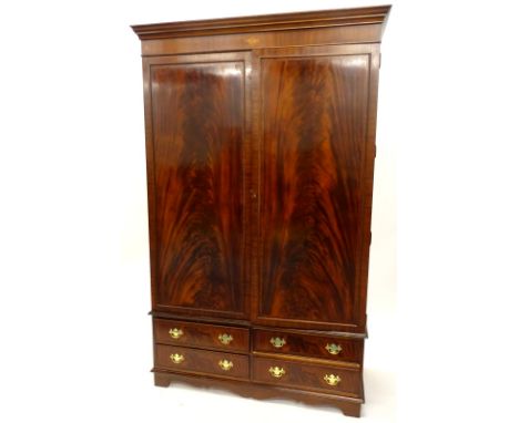 A mahogany wardrobe, with a moulded cornice oval and circular pattera inlaid frieze, above two panelled doors enclosing a han
