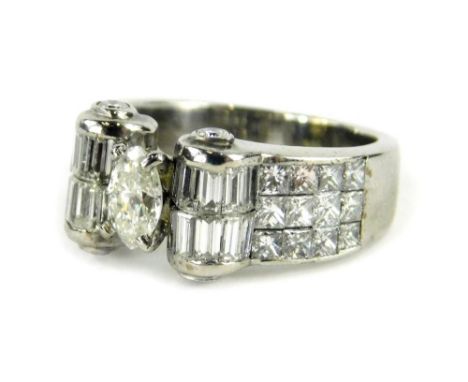 A diamond dress ring, with central marquise cut diamond, in four claw setting, with scroll to each side set with baguette cut