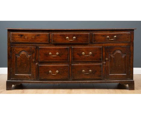 A 19th century oak dresser base of three long drawers over four short drawers and pair of cupboard doors, on bracket feet, 17
