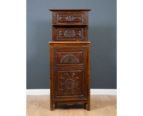 An 18th century oak bread cupboard with carved floral rosettes, the high back with shelf over cupboard base concealing integr