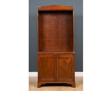 A mahogany open fronted bookcase with pediment top, the pair of cupboard doors with fitted shelf below racked shelving, on br