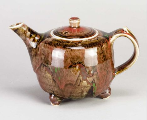 † MARGARET FRITH (born 1943) for Brookhouse Pottery; a porcelain teapot on tripod feet covered in copper red and tenmoku glaz