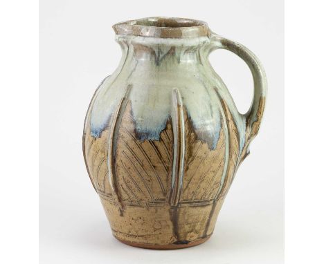 † MIKE DODD (born 1943); a stoneware jug covered in green ash glaze with incised and applied decoration and running nuka top,