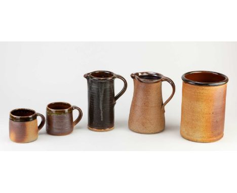 Muchelney Pottery; a group of stoneware ceramics comprising a utensil jar, two jugs and a near pair of mugs, impressed potter