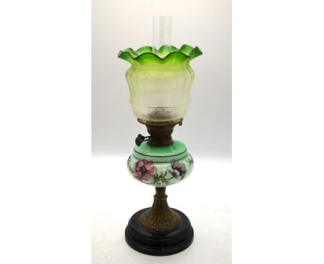 A late Victorian oil lamp with floral etched green glass shade, opaque glass font painted with poppies, brass stem and black 