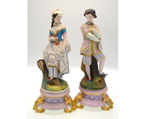 A matched pair of continental bisque figures of a lady and gentleman standing beside a tree trunk, impressed HC to base of th