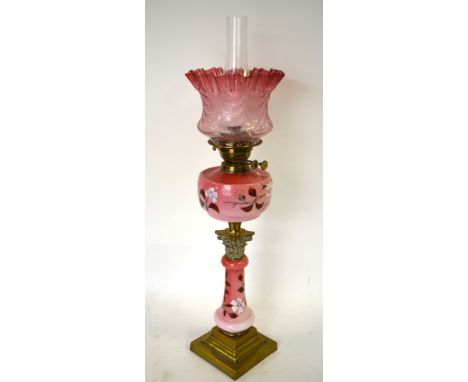 A Victorian floral-painted pink glass oil lamp with brass mounts and etched glass cranberry shade Condition Report No damage 