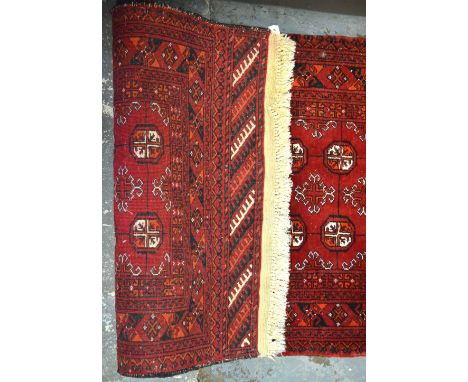 A contemporary Afghan Turkoman design runner, the dark geometric design on red ground, 7 x 0.75 m