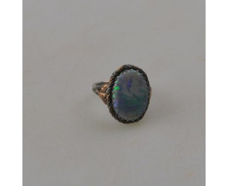 An Arts & Crafts single stone black opal ring, claw set in silver and copper