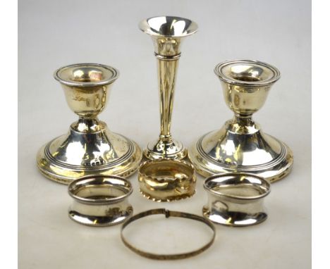 A pair of loaded silver low candlesticks, Birmingham 1915, to/w two napkin rings, a small flute vase and a bangle