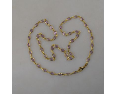 An oval faceted amethyst necklace in spectacle chain settings, yellow metal stamped 750