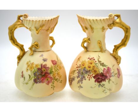 A matched pair of Royal Worcester blush ground jugs decorated with wild flowers, coral formed handles, shape 1507, 21.5 cm h.