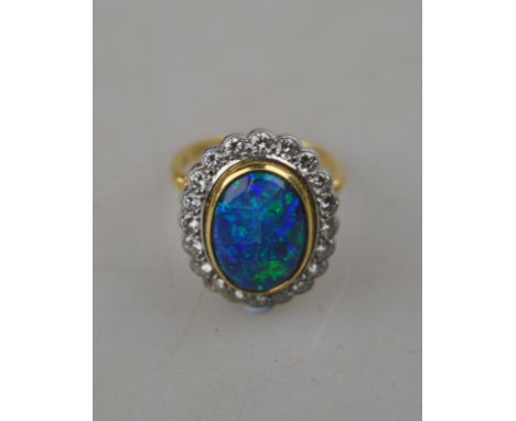 An oval black opal ring having brilliant cut diamonds around, in open basket style setting, 18ct white and yellow gold set Co