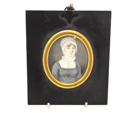 A Regency oval portrait miniature of an attractive young lady in lace cap and grey dress, unsigned, 6.5 x 5.5 cm, in ebonised