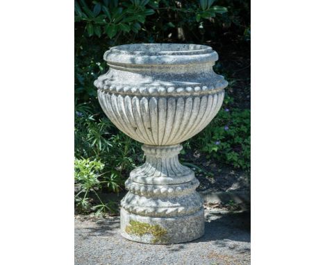 A LARGE CARVED STONE FLUTED URN  19TH CENTURY  Set on a separate plinth base  97cm high overall, 68cm diameter    Provenance: