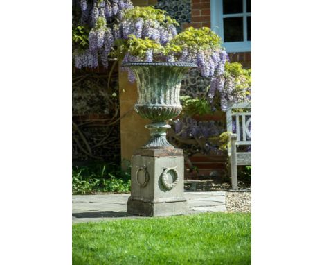 A LARGE FLUTED CAST IRON CAMPANA VASE ON COMPOSITION STONE BASE  19TH CENTURY  126cm high overall, the urn 77.5cm high, the b