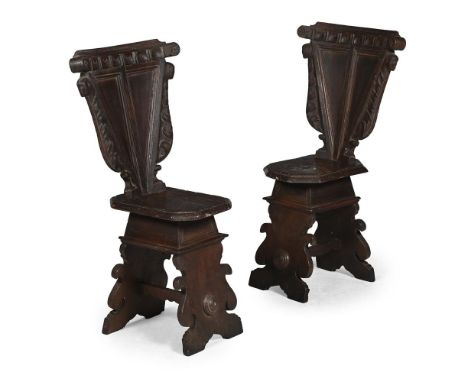 A PAIR OF ITALIAN CARVED WALNUT SGABELLO HALL CHAIRS PROBABLY TUSCANY, 16TH OR EARLY 17TH CENTURY The triangular panelled bac