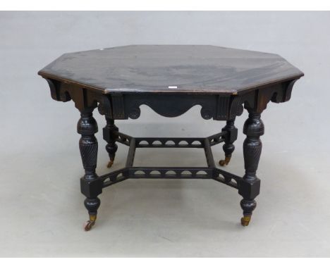 AN EBONISED OCTAGONAL TABLE WITH A WAVY APRON ABOVE THE SPIRALLY FLUTED BALUSTER LEGS JOINED BY ARCH PIERCED STRETCHERS ABOVE