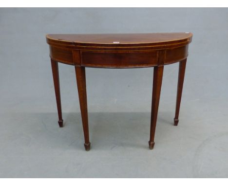 A GEORGE III MAHOGANY DEMI LUNE GAMES TABLE, THE SATIN WOOD CROSS BANDED TOP OPENING ON SINGLE GATE, THE TAPERING SQUARE LEGS