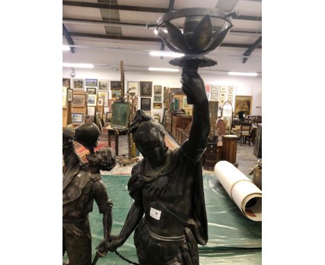 A LARGE SPELTER FIGURAL TABLE LAMP OF AN INDIAN WARRIOR HOLDING ALOFT A FLAME, TOGETHER WITH TWO OTHER SPELTER FIGURES. THE L
