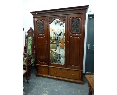 AN EDWARDIAN MAHOGANY WARDROBE, THE CENTRAL SERPENTINE TOPPED BEVELLED GLASS MIRROR FLANKED BY DOORS EACH WITH FOLIATE CARVED