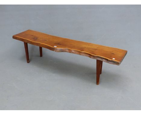 A REYNOLDS OF LUDLOW YEW WOOD BENCH, THE SEAT A SECTION OF TRUNK SUPPORTED ON FOUR CYLINDRICAL LEGS, BRASS LABELLED.   W 154 