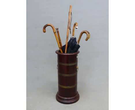 A BRASS BOUND MAHOGANY STICK STAND WITH LION MASK AND RING HANDLES.   H 63cms. TOGETHER WITH TWO OF EACH, UMBRELLAS, WALKING 