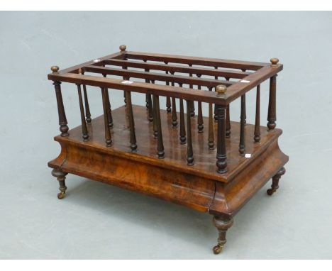 A BURR WALNUT THREE COMPARTMENT CANTERBURY, THE BAIZE LINED DRAWER WITH THE FRONT DOWNSWEPT TO BALUSTER LEGS ON CERAMIC CASTE