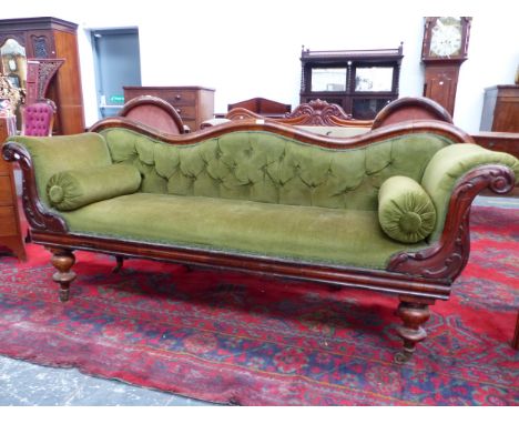 A VICTORIAN MAHOGANY SHOW FRAME SETTEE BUTTON BACKED BELOW A SERPENTINE TOP RAIL. THE FRONTS OF THE ROLL OVER ARMS CARVED WIT