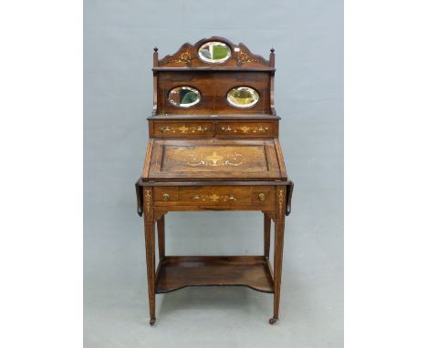 A LATE VICTORIAN MARQUETRY INLAID ROSEWOOD BUREAU, THE SHELVES RECESSED BEHIND THE FALL INSET WITH THREE OVAL MIRRORS, THE DR
